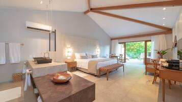 A modern bedroom with a large bed, bedside tables, a desk, and a bench.