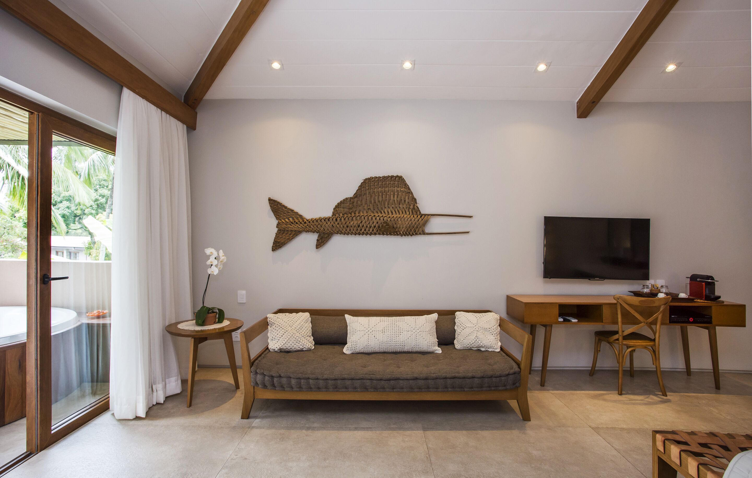 Una sala de estar moderna con un sofá, un televisor, un escritorio de madera y una gran pieza de arte mural con motivos de peces.