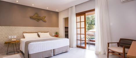Un dormitorio moderno con una cama grande, una mesita de noche de madera, una silla y vistas al exterior a través de un ventanal.