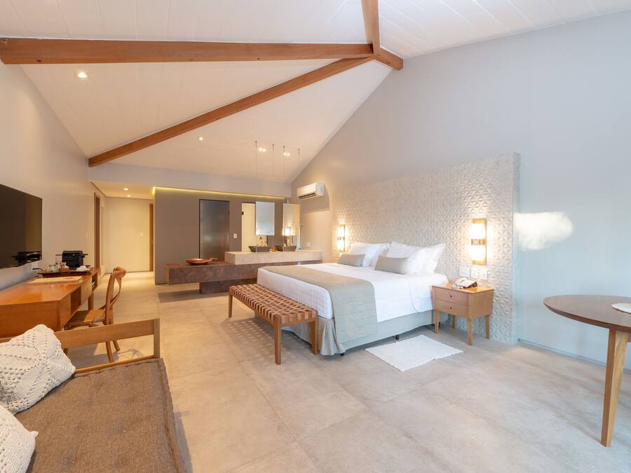 A modern bedroom with a large bed, bedside tables, a desk, and a TV.