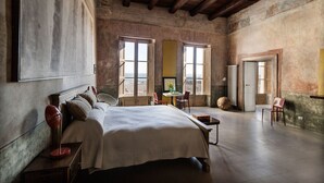 Une chambre spacieuse avec un grand lit, des poutres apparentes et de grandes fenêtres.