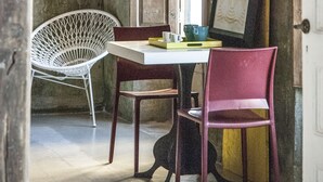 Une pièce avec une table blanche, deux chaises, un tableau encadré et une porte en bois.