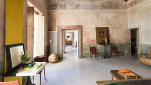 Une pièce spacieuse avec un plafond haut, un coin repas avec une table et des chaises, et une vue sur une autre pièce accessible par une porte ouverte.