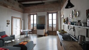 A spacious living area with a sofa, a dining table, and a kitchen area with a sink and stove.