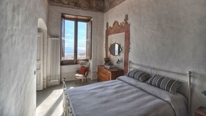 A bedroom with a bed, dresser, chair, and a window with a view.