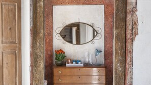 A room with a wooden dresser, a mirror, and a vase with flowers.