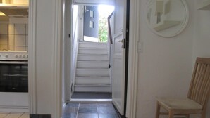 A staircase leading to a second floor, a kitchen area with an oven, and a chair in a hallway. - Guesthouse Sharon Aarhus (Aarhus)