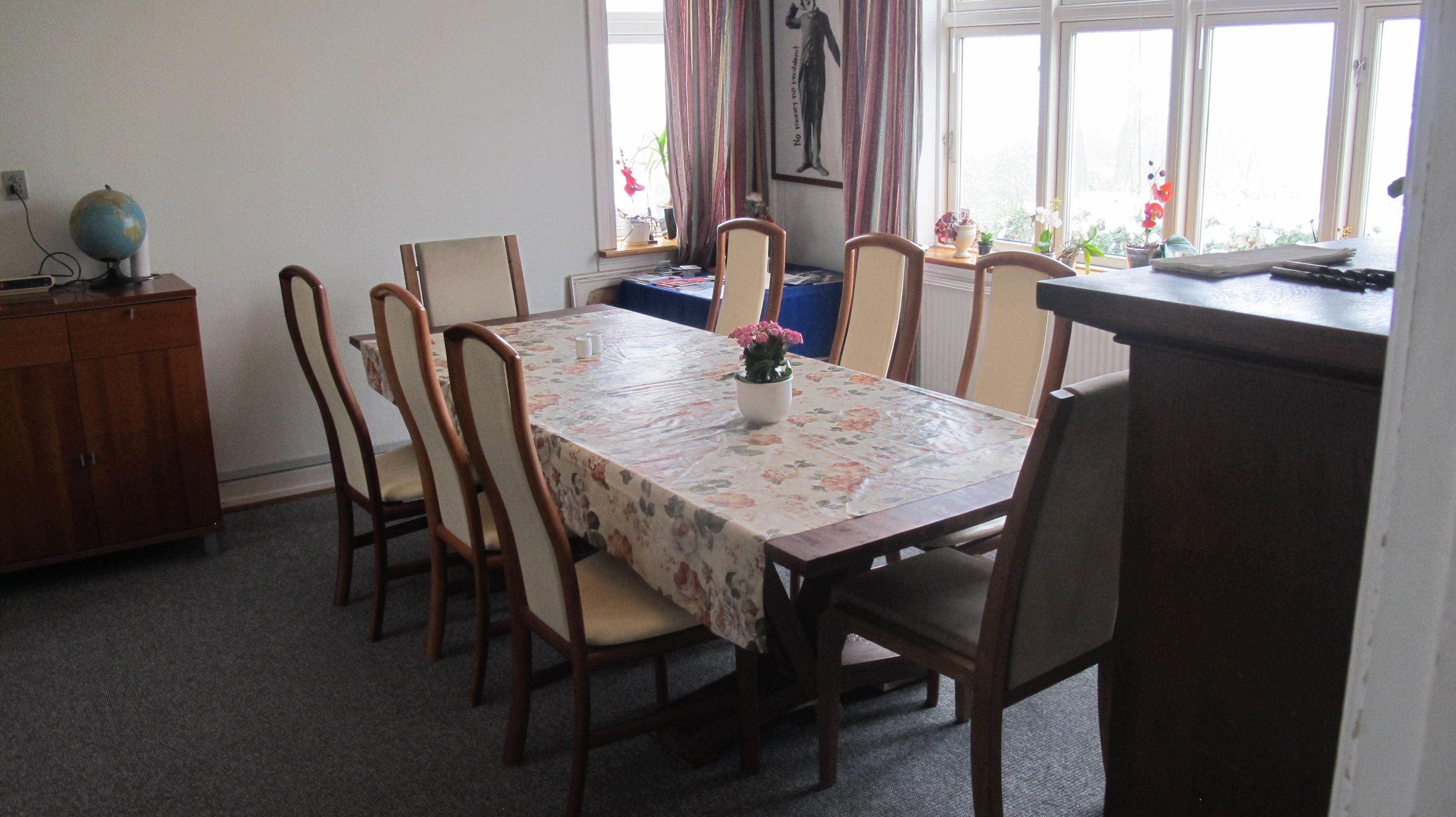 A dining room with a table set for six, surrounded by wooden chairs.