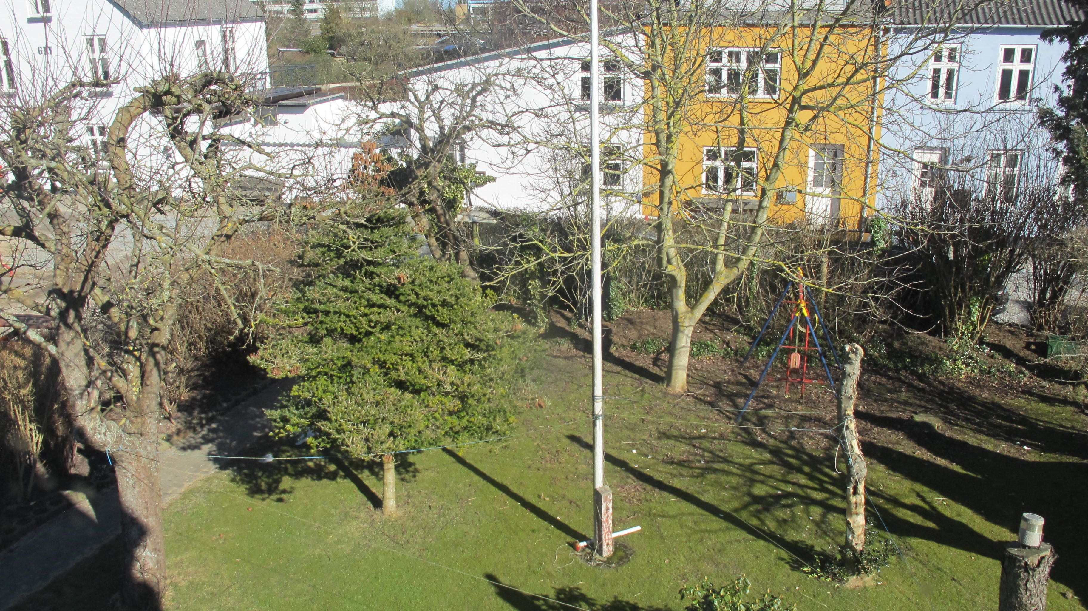 A residential area with houses, a grassy lawn, and trees.