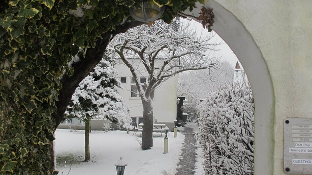 A snow-covered pathway leading to a building with a bench and a lamppost. - Guesthouse Sharon Aarhus (Aarhus)