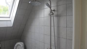 Un baño con ducha, inodoro y ventana.