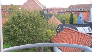 A residential area with red-tiled roofs, a blue building, and a tree in the foreground.