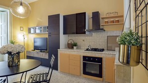 A modern kitchen with a dining area, a TV, and a hanging plant. - Chez Mamie Flat (Salerno)