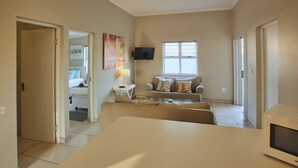 A modern living room with a sofa set, a flat-screen TV, and a dining table. - The Nook, Langebaan 4-Sleeper (Langebaan)