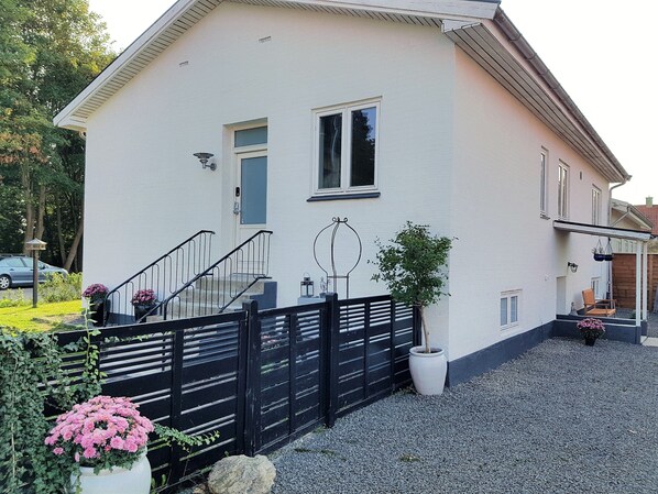 A two-story house with a white exterior, a black gate, and a gravel driveway. - Køge Guesthouse (Koge)