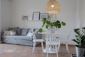 A modern living room with a grey sofa, white chairs, a round table, and a hanging wicker light fixture. - Casa Giada (Salerno)