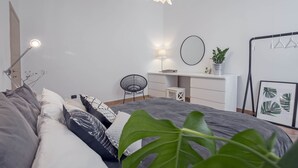 A modern bedroom with a bed, bedside lamp, desk, chair, and a hanging plant. - Casa Giada (Salerno)