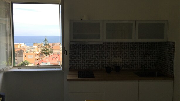 A small kitchen with a window overlooking a cityscape and the sea. - Sole Flat (Minori)