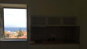A kitchen with a view of the sea, a tiled backsplash, and a window with a view of buildings. - Sole Flat (Minori)