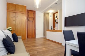 Una sala de estar moderna con sofá, mesa de comedor, televisor y armarios de madera.