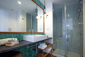 Un baño moderno con un espejo grande, un lavabo y una zona de ducha.