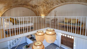 A high-ceilinged room with a white railing, a loft bed, and three hanging wicker lamps. - Castello Mezzacapo by Starhost (Scala)
