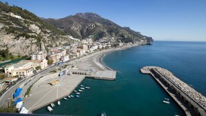 A coastal town with a marina, buildings along the waterfront, and a mountainous backdrop. - Castello Mezzacapo by Starhost (Scala)