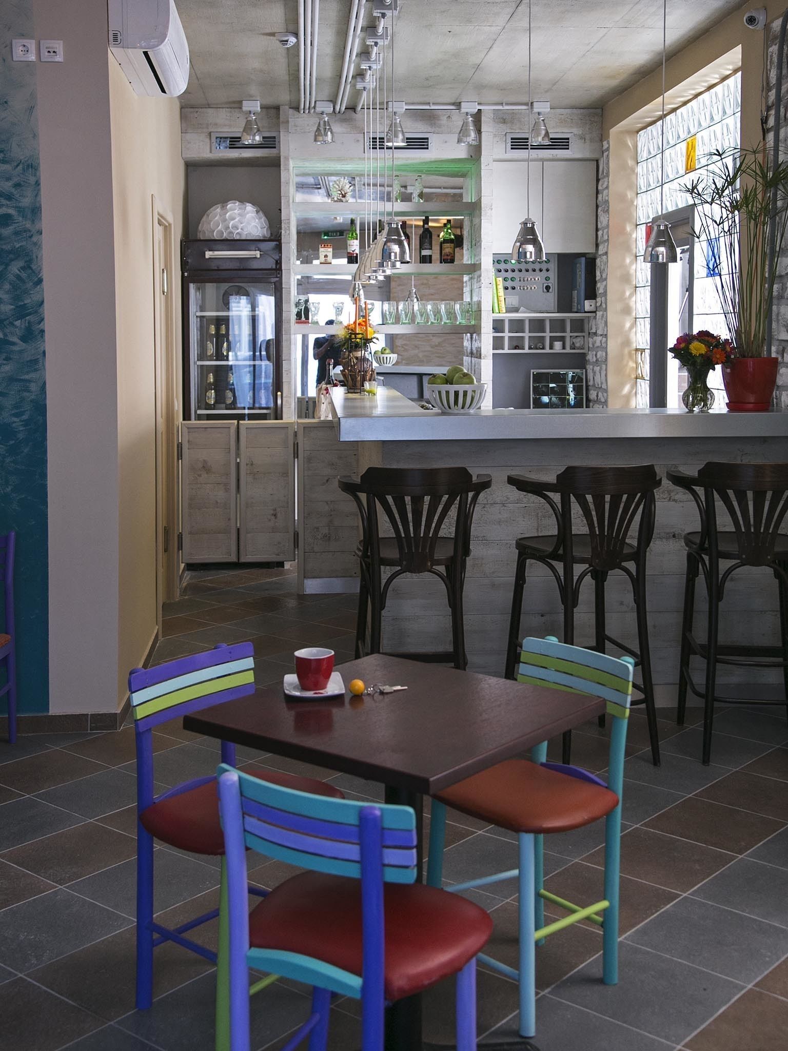 A modern kitchen with a dining area, featuring a central island, bar stools, and a colorful chair arrangement.