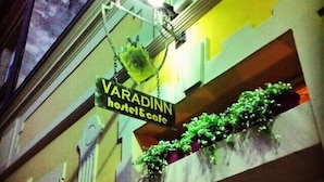 A sign for 'VARADINN hostel & cafe' with a balcony adorned with potted plants. - Varad Inn Hostel and Cafe (Novi Sad)