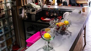 A bar area with hanging lights, a counter with a fruit basket, and a chalkboard menu. - Varad Inn Hostel and Cafe (Novi Sad)