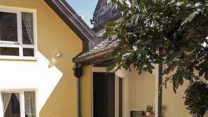 A patio with outdoor seating, a laptop on a table, and a bowl of fruit. - Varad Inn Hostel and Cafe (Novi Sad)