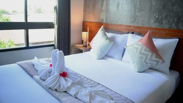 Habitación de hotel con una cama grande, un cabecero de madera y una ventana con cortinas.