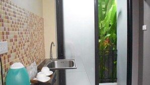 Una cocina compacta con un lavamanos, una tetera y una pequeña encimera.