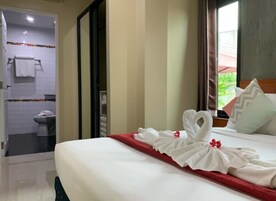 Habitación de hotel con una cama bien hecha, baño con ducha e inodoro, y vistas a zonas verdes.