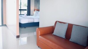 Habitación de hotel moderna con una cama grande, un sofá de cuero marrón y vistas al exterior.