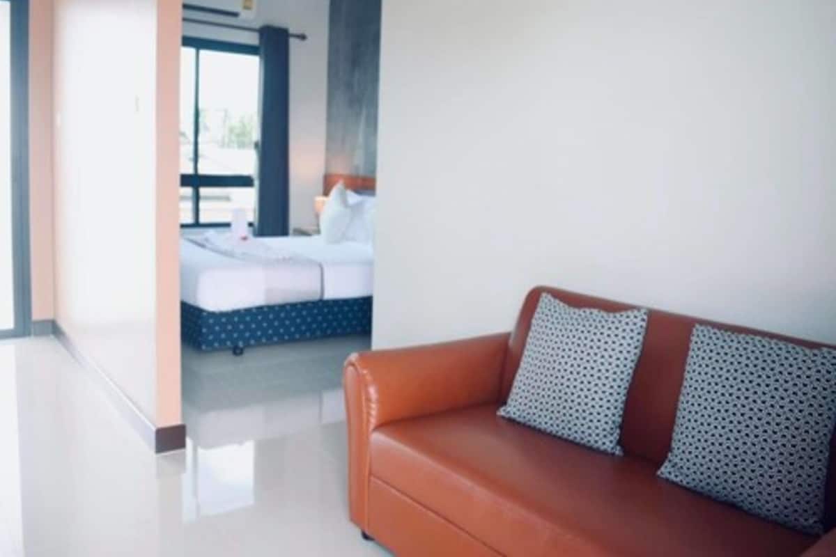 A modern hotel room with a large bed, a brown leather sofa, and a view of the outside.