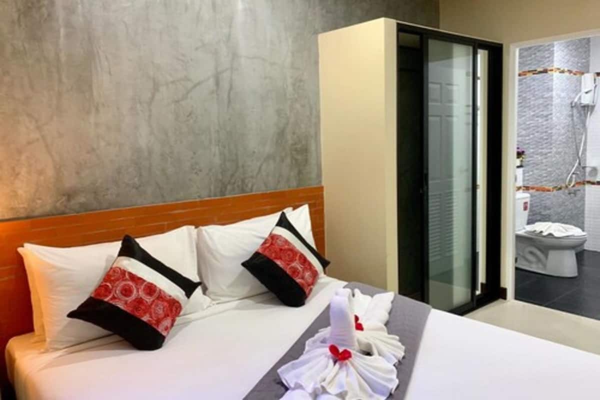 A hotel room with a bed, pillows, a towel, and a view of the bathroom.