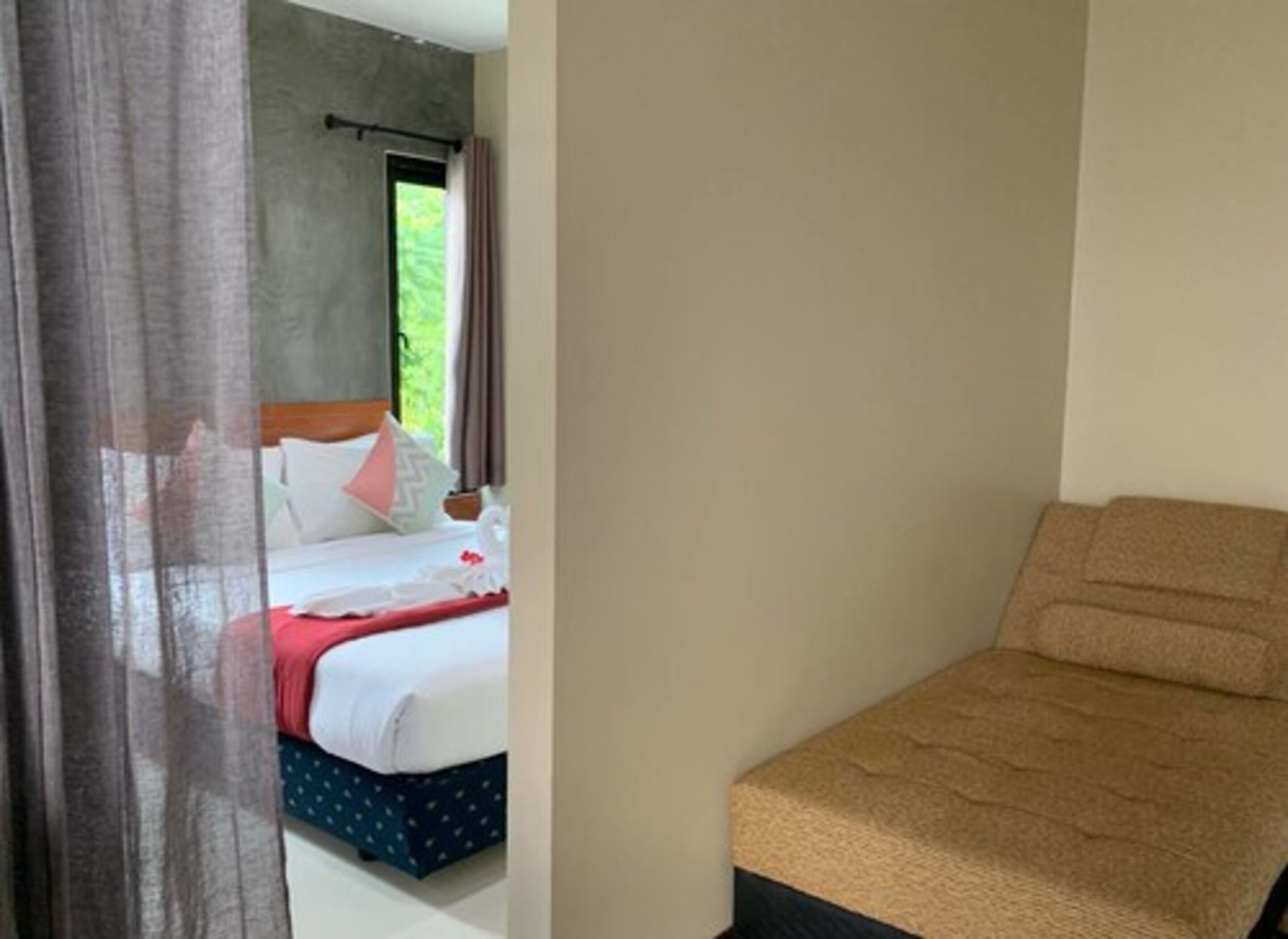 A hotel room with a bed, a small sofa, and a window with curtains.