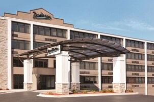A Radisson hotel with a covered entrance, stone pillars, and a clear sky.
