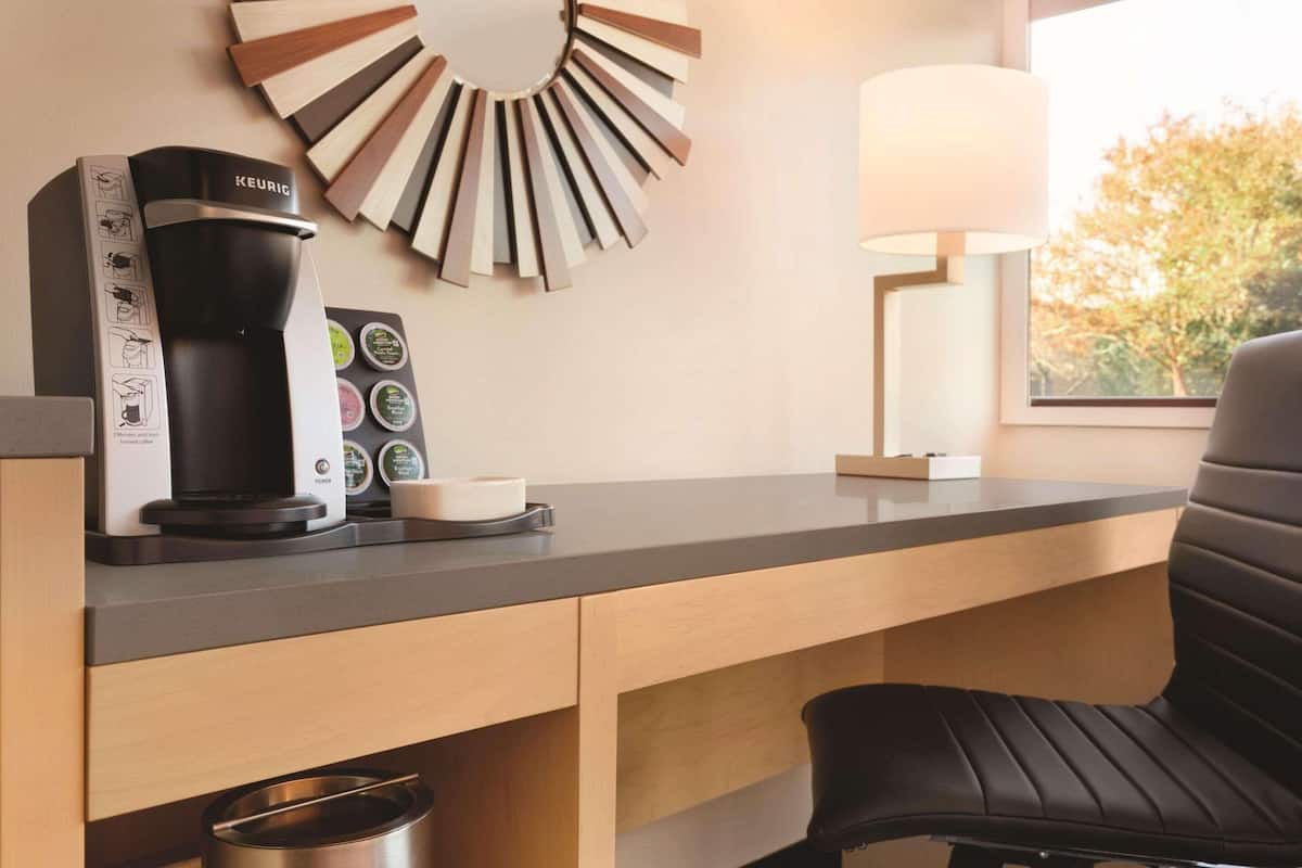 Een moderne keuken met een Keurig koffiezetapparaat, een houder voor koffiekapsules en een koffiekan op het aanrecht.