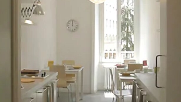 A narrow hallway with a dining area at the end, featuring a large window with a view of buildings. There are two pendant lights hanging from the ceiling. - Il Sampietrino dei Cavalleggeri B&B (Rome)
