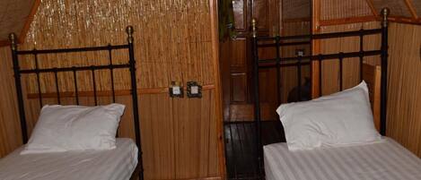 A room with two beds, wooden walls, and a sloped ceiling.