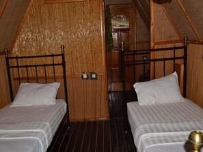 Une chambre avec deux lits, des murs en bois et un plafond en pente.