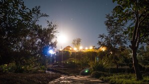 A stone pathway leading to a building with string lights and a warm glow. - Rwiza Village (Mubuga)