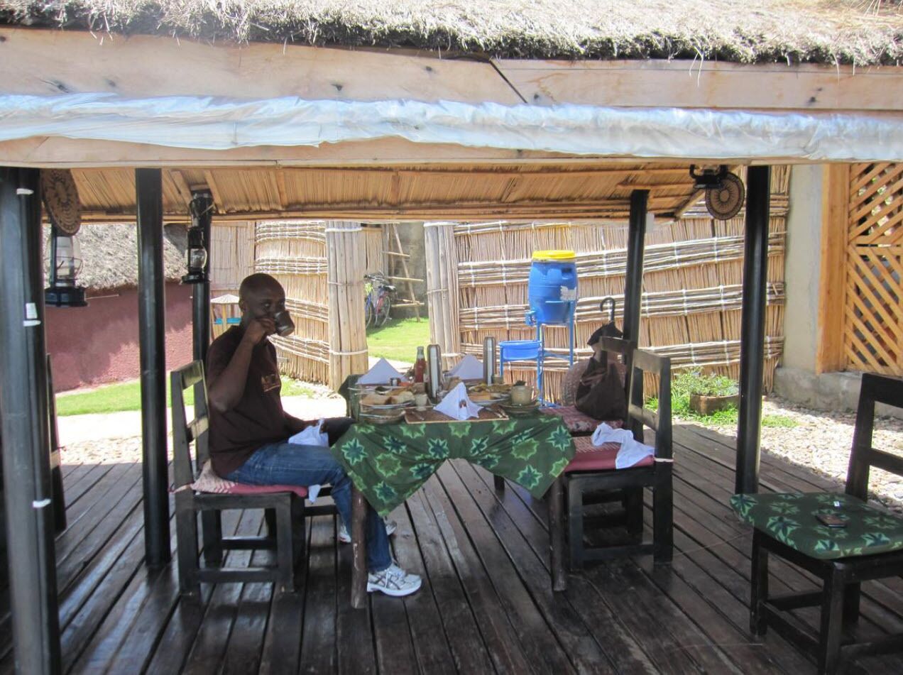 A covered outdoor seating area with wooden furniture and a table set for two.
