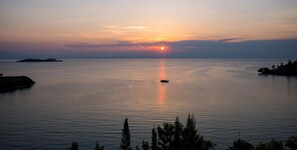 Un plan d’eau paisible, avec un bateau au loin et un coucher de soleil en arrière-plan.