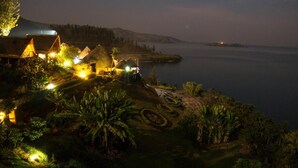 A coastal resort with thatched-roof cottages, a well-maintained garden, and a view of the sea. - Rwiza Village (Mubuga)