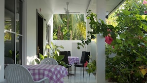An outdoor patio with a table and chairs, surrounded by lush greenery and a view of the outdoors. - Athiriveli (Thoddoo)