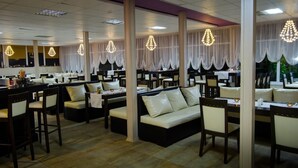 A restaurant with multiple dining areas, including booths and tables, with chandeliers and draped curtains. - Tropics Hotel (Sveti Vlas)
