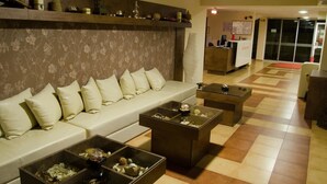 A lobby with a sofa, coffee tables, and a reception desk. - Tropics Hotel (Sveti Vlas)